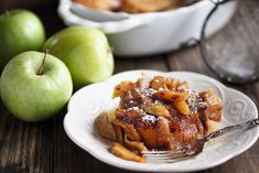 an apple dessert on a white plate next to green apples