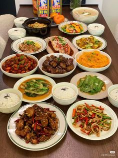 a table topped with lots of white plates filled with different types of food and veggies