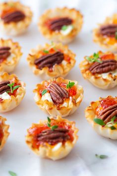 small appetizers are arranged on a white plate with garnishes and pecans