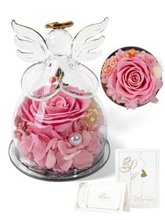 a glass vase filled with pink flowers next to a greeting card and an angel figurine