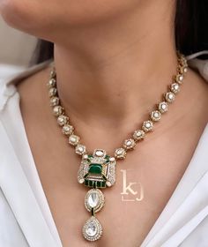 a woman wearing a necklace with green and white stones on the bottom, along with a pair of earrings