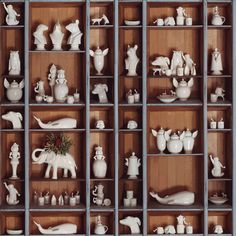 a shelf filled with lots of white figurines on top of wooden shelves next to each other