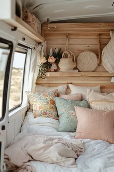 the interior of a camper with lots of pillows and blankets on it's bed