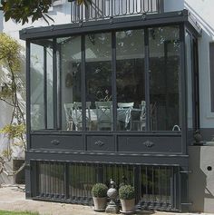 a house that has some plants in front of it and two potted plants on the outside