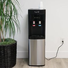 a water dispenser sitting next to a potted plant on the floor