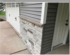 the side of a house with a garage door and window on it's side