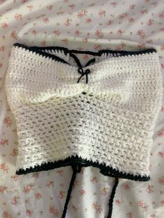 a crocheted white and black bralet laying on top of a flowered sheet