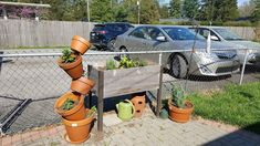 there are many potted plants on the side of this fenced in parking lot