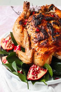 a whole chicken on a plate with pomegranates