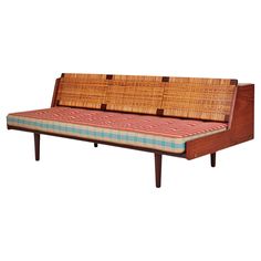 a couch made out of wood and wicker with plaid fabric on the seat cushion