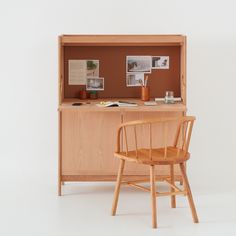 a wooden chair sitting next to a desk with pictures on it