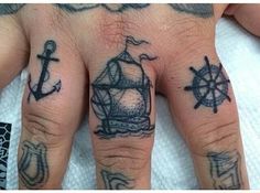 a person's hand with tattoos on it and an anchor, ship wheel and compass