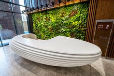 a large white bench sitting in front of a wall with green plants on it's sides