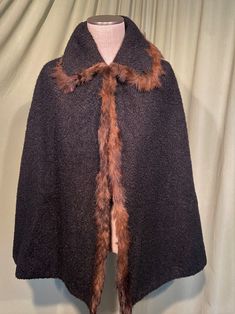 "This is a lovely, vintage antique nubby wool cape. It dated from the early 1900's, possibly earlier or so. No brand labels, no size tags. It is a lovely, black nubby wool with brown shaggy fur trim on the collar & front edges. The collar is rather large & is nubby wool on the underside. It closes with 4 sets of metal hooks & eyes. Lined with black cotton sateen. The lining seam is open on one front edge for about 12\". You can see the construction inside. Between the nubby wool & the lining is Vintage Black Cape For Winter, Vintage Black Winter Cape, Vintage Winter Poncho One Size, Vintage One-size Winter Poncho, One Size Vintage Poncho For Winter, Vintage Wool Cape Outerwear, Vintage Brown Winter Cape, Vintage Cape For Fall, Vintage Cape For Fall Costume