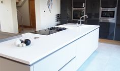 a modern kitchen with white counter tops and stainless steel appliances in the backround