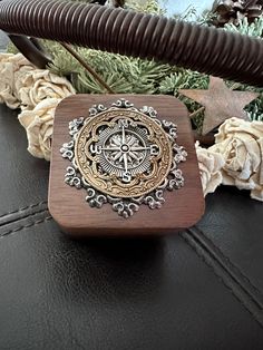 a wooden box sitting on top of a table next to some flowers and branches in the background