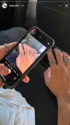 a person holding a cell phone in their hand while sitting in the back seat of a car