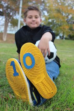 a young boy sitting in the grass holding a soccer ball