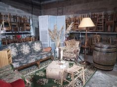 a living room filled with furniture and lots of wooden shelves on the wall behind it