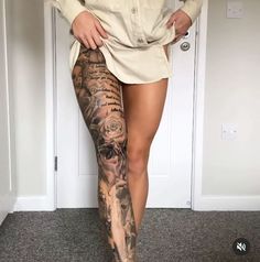 a woman is standing in front of a door with tattoos on her legs and leg