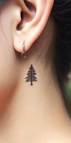 A finely detailed, realistic tree tattoo lurks behind the ear, subtly expressing the wearer's deep connection to nature. Discover our 'TreeTee' Etsy shop - every tee bought aids in planting a tree, making your style choice a contribution towards a healthier planet. Travel Tattoo Behind Ear, Mountain Tattoo Behind Ear, Finger Tree Tattoo, Traditional Tree Tattoo, Behind Ear Tattoo Unique, Tree Ring Tattoo, Redwood Tattoo, Tattoo Behind The Ear, Acorn Tattoo