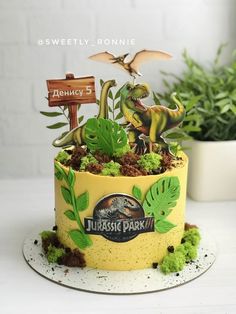 there is a cake decorated with dinosaurs and plants