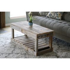 a wooden coffee table sitting on top of a white rug next to a gray couch