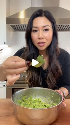 a woman holding up a spoon over a bowl filled with food