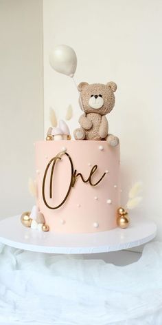 a teddy bear sitting on top of a pink cake