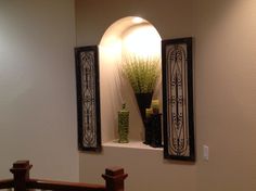 an arched window with decorative iron work on the wall and below it is a potted plant