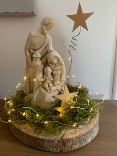 a nativity scene is displayed on a table with a star and string lights in the background