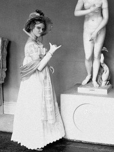 an old black and white photo of two women standing in front of a nude statue