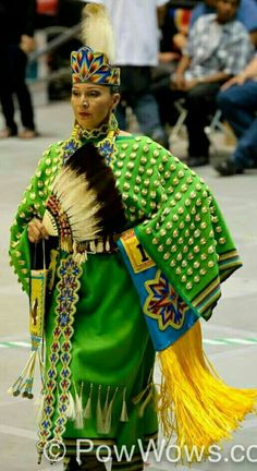 a woman in green and yellow costume walking down the street with her hand on her hip