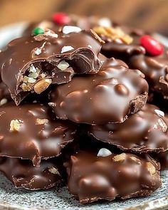 a plate full of chocolate covered cookies with nuts on top and candy in the middle