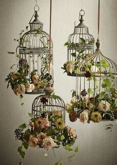 three bird cages with flowers hanging from them