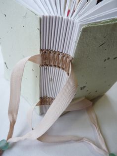 an open book with ribbon on it sitting on a table next to a white surface