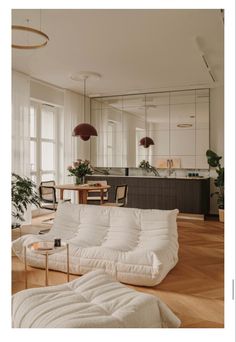 a living room filled with furniture next to a kitchen and dining room table on top of a hard wood floor