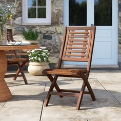 a wooden chair sitting on top of a stone floor next to a table and chairs