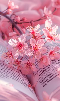 an open book with pink flowers on the pages and in the background is a tree branch