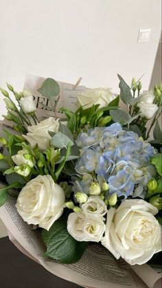 a bouquet of white and blue flowers sitting on top of an open book with leaves