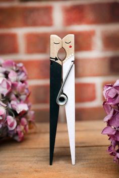 a pair of scissors that are sitting on a table next to some flowers and a brick wall