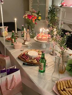 a table topped with lots of food and candles next to bottles of wine on top of a table