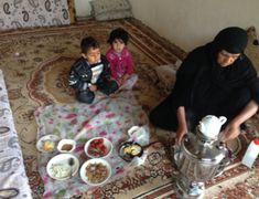 a woman and two children are sitting on the floor with bowls of food in front of them