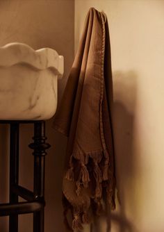 a towel hanging on the wall next to a white sink and black stool with an old fashioned faucet