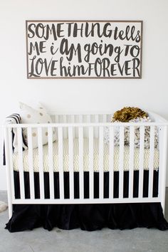 a white crib in a room with a black and white sign on the wall