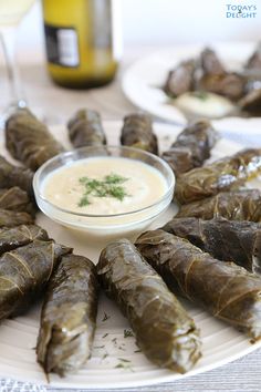 some stuffed grape leaves are on a plate with dipping sauce in the middle and words that read, dolmades greek stuffed grape leaves