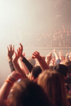 a crowd of people at a concert with their hands in the air