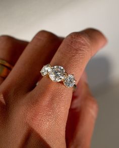 a woman's hand holding a three stone diamond ring