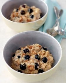 two bowls filled with oatmeal and blueberries on top of a table