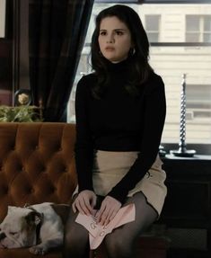 a woman sitting on top of a brown couch next to a white and black dog